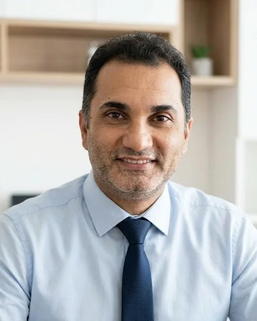 Yunus Amaç, ofisinde masa başında, takım elbise ve kravatla
